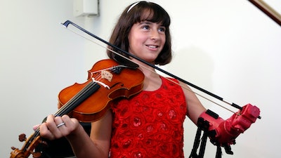 Ten-year-old Isabella Nicola Cabrera smiles after playing her violin with her new prosthetic at the engineering department of George Mason University in Fairfax, Va., Thursday, April 20, 2017. 'Oh my gosh, that's so much better,' Isabella said as she tried out the new prosthetic.