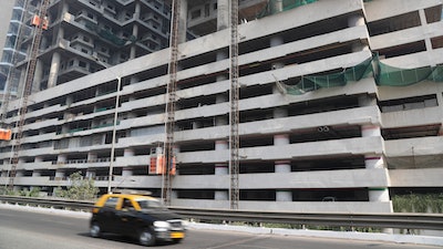 In this Tuesday, Jan. 21, 2020, file photo, a car drives past an under-construction building in Mumbai, India, Tuesday, Jan. 21, 2020. India’s government expects the economy to expand up to 6.5% in the next fiscal year, starting in April, and hopes to follow China's example in developing labor intensive industries and exports.