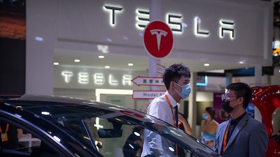Staff members talk near vehicles at a display for automaker Tesla at the China International Fair for Trade in Services (CIFTIS) in Beijing on Sept. 2, 2022.